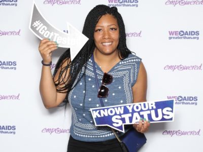 Woman holding an #IGotTested and a "Know Your Status" signs